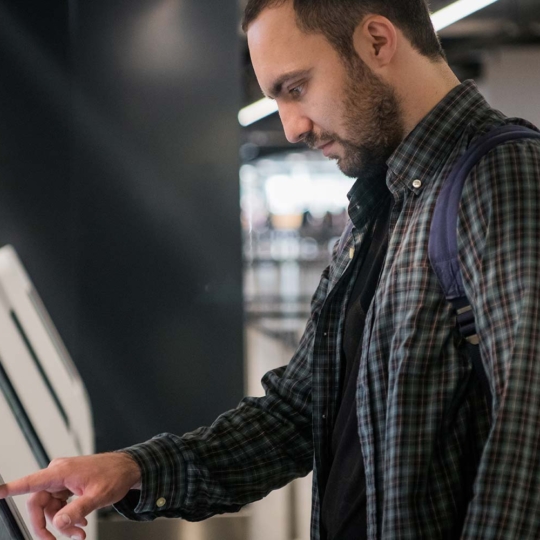 Young Man Operates Kiosk Integrated with Open Frame Touch Display